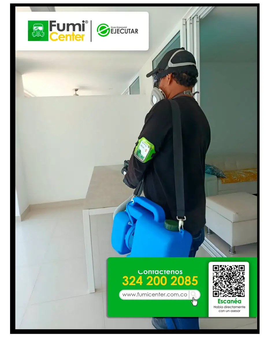 Técnico de FumiCenter con aspersor manual en la habitación de un apartamento